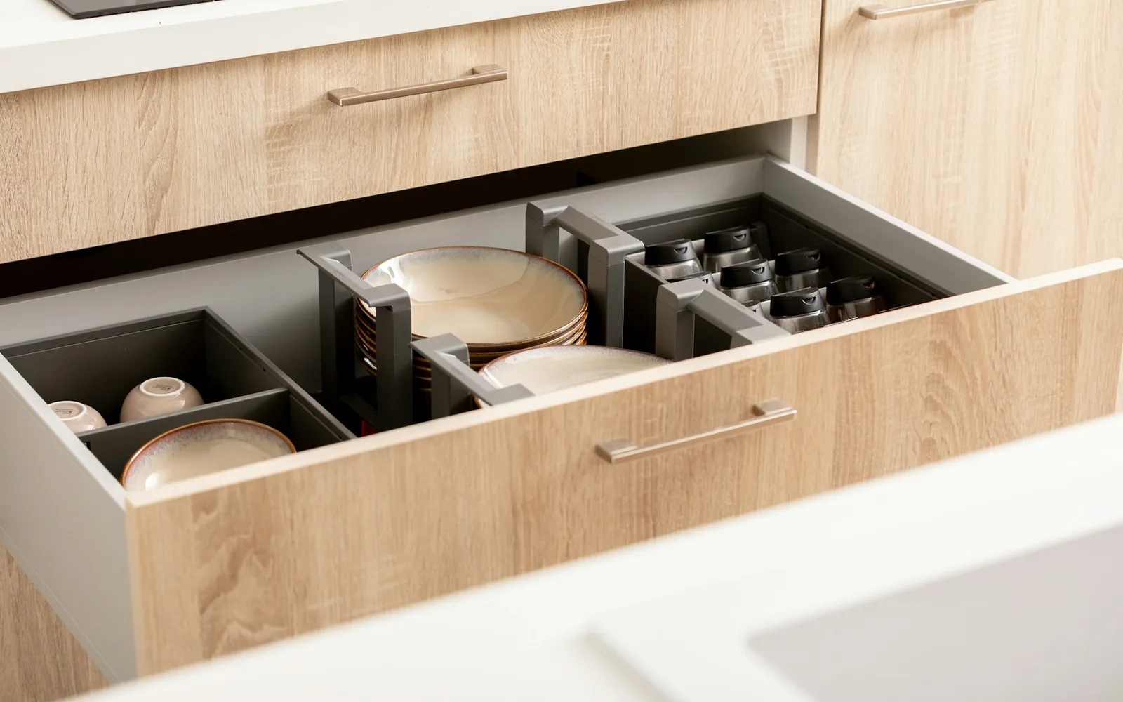 An organized kitchen drawer with plates, spices, and cups