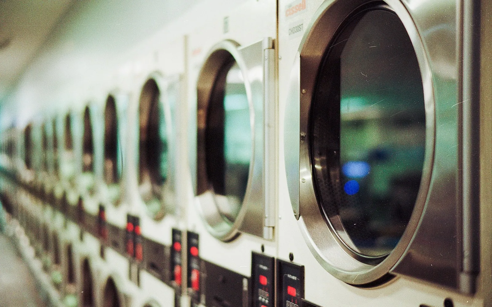 A row of laundry machines in an everyday laundry setting