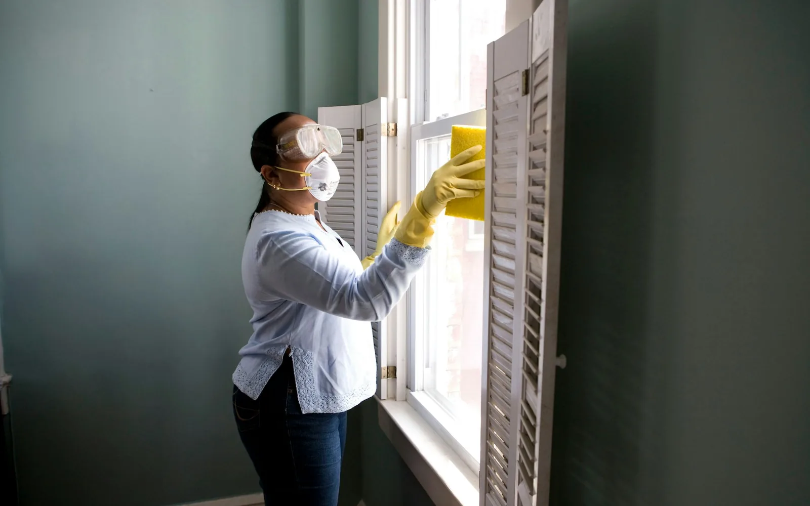 A person cleaning a window in a lived-in home